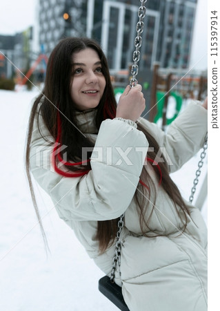 Woman Sitting on Swing in Snow 115397914