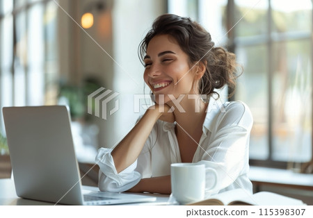 Smiling Woman Sitting at Desk With Coffee and Laptop 115398307