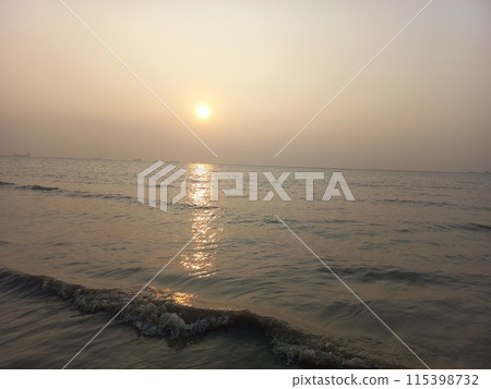 The silhouette of the sunset over the tropical sea paints an inspirational horizon. The seascape of the tropical beach, with its orange and golden sky, evokes a sense of tranquility, relaxation, and t 115398732