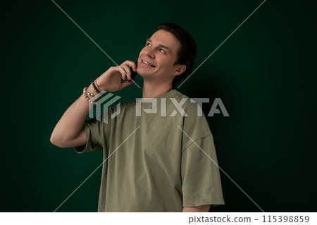 Man Talking on Cell Phone in Front of Green Wall 115398859