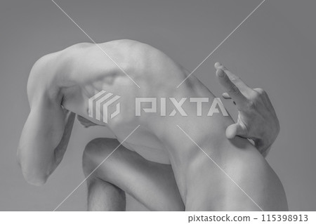 Human form in dynamic pose emphasizing motion and strength. Monochrome photography highlighting muscles and curves of defined male body. Human form in dynamic pose emphasizing motion and strength. Monochrome photography highlighting muscles and curves of defined male body. 115398913