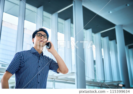 A young businessman wearing a short-sleeved shirt making a phone call 115399634