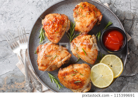 Baked Rosemary Lemon Chicken thighs served with ketchup close-up in a plate. Horizontal top view 115399691