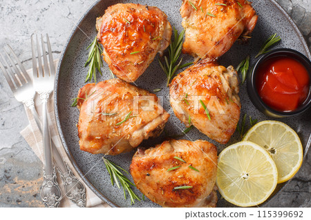 Delicious homemade Lemon rosemary chicken thighs served with ketchup close-up in a plate. Horizontal top view 115399692