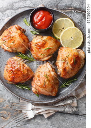 Lemon rosemary chicken thighs served with ketchup close-up in a plate. Vertical top view 115399694