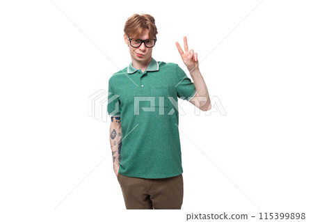 young stylish cheerful european guy with red hair with a tattoo on his forearm wears a green t-shirt young stylish cheerful european guy with red hair with a tattoo on his forearm wears a green t-shirt 115399898
