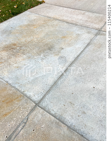 A close-up view of a concrete driveway showcasing repaired joints and cracks. The fixed areas demonstrate effective maintenance, enhancing the driveways durability and appearance. 115400214