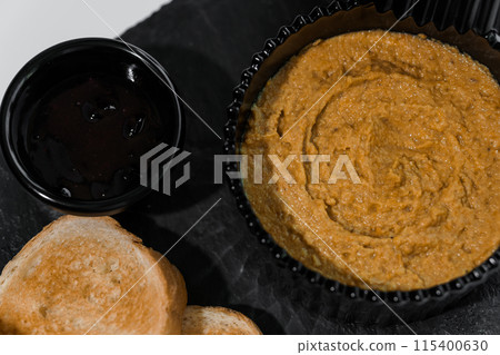 Pate with sauce and croutons on a black board on a white background 115400630