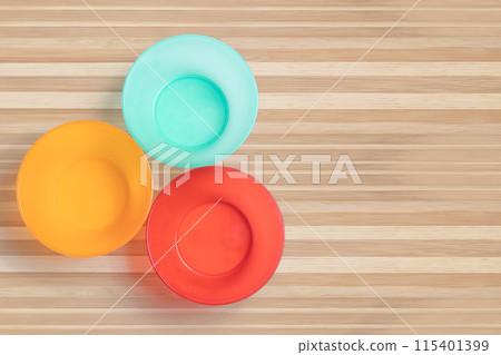 Three different colored plastic empty bowl on wooden table. 115401399
