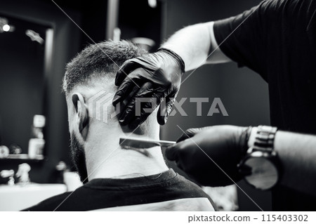 A man is getting his hair cut by a barber A man is getting his hair cut by a barber 115403302