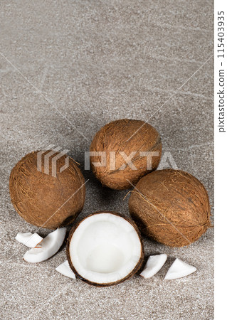 Whole coconuts and half a coconut on a blue and gray background close-up Whole coconuts and half a coconut on a blue and gray background close-up 115403935
