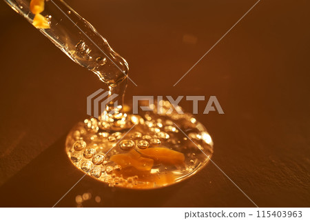Pipette with serum shimmering in the sun on a beige background. 115403963