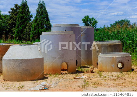 Construction site drainage wells stacked before installation 115404833