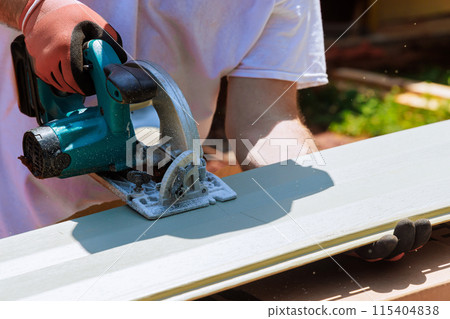 As part of construction process, craftsman cuts vinyl siding panels to desired size before installing them As part of construction process, craftsman cuts vinyl siding panels to desired size before installing them 115404838