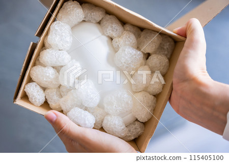 Eco packaging of parcels and white biodegradable filler. Box is filled with a filler safety for environment. Delivery of goods, parcels, delivery service, nature protection and recycling concept Eco packaging of parcels and white biodegradable filler. Box is filled with a filler safety for environment. Delivery of goods, parcels, delivery service, nature protection and recycling concept 115405100
