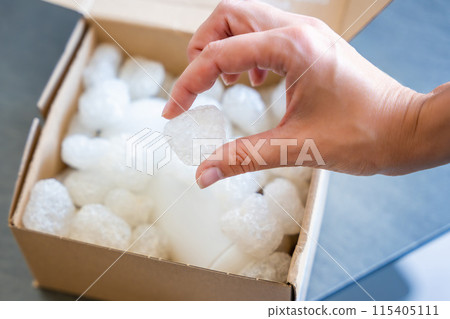 Eco packaging of parcels and white biodegradable filler. Box is filled with a filler safety for environment. Delivery of goods, parcels, delivery service, nature protection and recycling concept Eco packaging of parcels and white biodegradable filler. Box is filled with a filler safety for environment. Delivery of goods, parcels, delivery service, nature protection and recycling concept 115405111