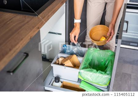 Woman throwing trash into household bins for waste sorting in the kitchen for recycle. Plastic, paper, bio and mixed waste. Sorting waste at home concept 115405112