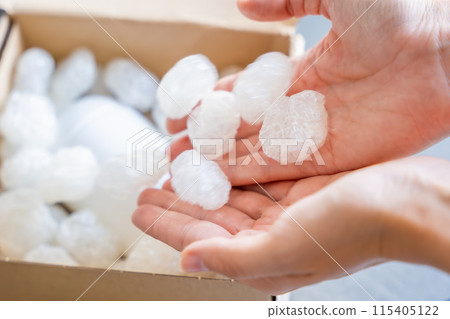 Eco packaging of parcels and white biodegradable filler. Box is filled with a filler safety for environment. Delivery of goods, parcels, delivery service, nature protection and recycling concept Eco packaging of parcels and white biodegradable filler. Box is filled with a filler safety for environment. Delivery of goods, parcels, delivery service, nature protection and recycling concept 115405122