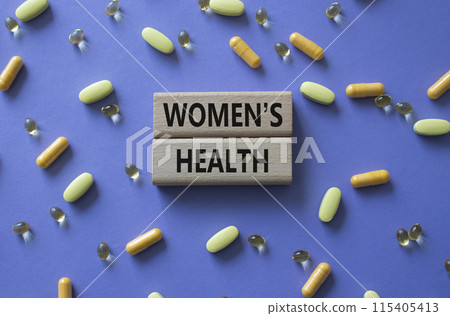 Womens health symbol. Concept word Womens health on wooden blocks. Beautiful purple background with pills. Medicine and Womens health concept. Copy space Womens health symbol. Concept word Womens health on wooden blocks. Beautiful purple background with pills. Medicine and Womens health concept. Copy space 115405413