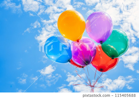 Bright colorful balloons against a blue sky with clouds Bright colorful balloons against a blue sky with clouds 115405688