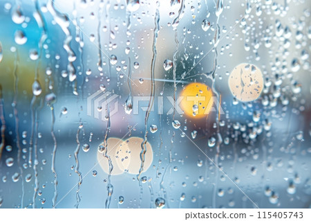 Raindrops on a window with blurred city lights in the background, creating a bokeh effect 115405743