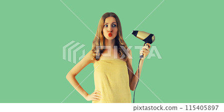 Beautiful young woman drying wet hair in wrapped bath towel after taking shower on green background Beautiful young woman drying wet hair in wrapped bath towel after taking shower on green background 115405897