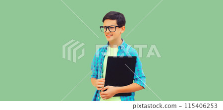 Happy smiling teenager boy in eyeglasses with folder or book on green background Happy smiling teenager boy in eyeglasses with folder or book on green background 115406253