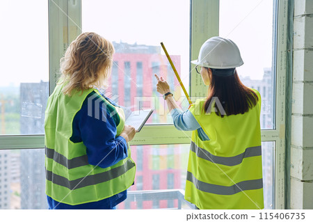Two female industrial workers taking measurements of windows for decoration Two female industrial workers taking measurements of windows for decoration 115406735