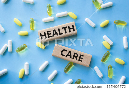 Healthcare symbol. Wooden blocks with words Healthcare. Beautiful blue background with pills. Medicine and Healthcare concept. Copy space. 115406772