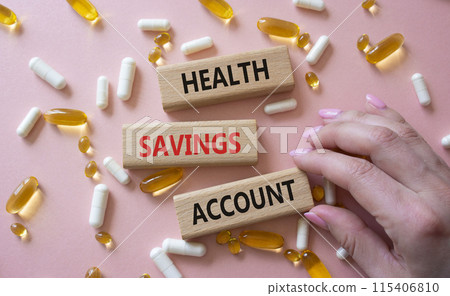 Health Saving Account symbol. Concept word Health Saving Account on wooden blocks. Doctor hand. Beautiful pink background with pills. Medicine and Health Saving Account concept. Copy space Health Saving Account symbol. Concept word Health Saving Account on wooden blocks. Doctor hand. Beautiful pink background with pills. Medicine and Health Saving Account concept. Copy space 115406810