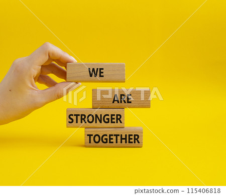 We are stronger together symbol. Wooden blocks with words We are stronger together. Businessman hand. Beautiful yellow background. We are stronger together concept. Copy space. 115406818