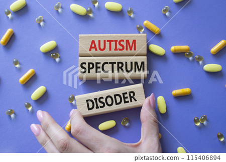 Autism Spectrum Disorder symbol. Concept word Autism Spectrum Disorder on wooden blocks. Doctor health. Beautiful purple background with pills. Medicine concept. Copy space 115406894