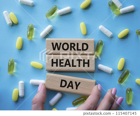 World Health Day symbol. Concept words World Health Day on wooden blocks. Beautiful blue background with pills. Doctor hand. Healthcare and World Health Day concept. Copy space. World Health Day symbol. Concept words World Health Day on wooden blocks. Beautiful blue background with pills. Doctor hand. Healthcare and World Health Day concept. Copy space. 115407145