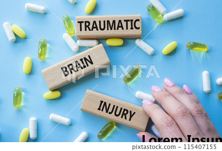 Traumatic Brain Injury symbol. Concept words Traumatic Brain Injury on wooden blocks. Beautiful blue background with pills. Doctor hand. Healthcare and Traumatic Brain Injury concept. Copy space. Traumatic Brain Injury symbol. Concept words Traumatic Brain Injury on wooden blocks. Beautiful blue background with pills. Doctor hand. Healthcare and Traumatic Brain Injury concept. Copy space. 115407155