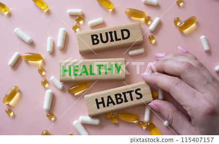 Healthy habits symbol. Concept word Build Healthy habits on wooden blocks. Doctor health. Beautiful pink background with pills. Healthy lifestyle and Healthy habits concept. Copy space 115407157