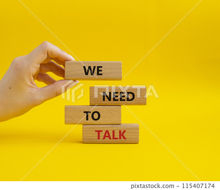 We need to talk symbol. Concept words We need to talk on wooden blocks. Beautiful yellow background. Businessman hand. Business and We need to talk concept. Copy space. 115407174