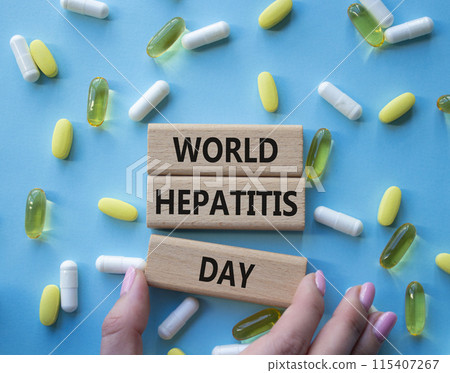 World Hepatitis Day symbol. Concept words World Hepatitis Day on wooden blocks. Beautiful blue background with pills. Doctor hand. Healthcare and World Hepatitis Day concept. Copy space. World Hepatitis Day symbol. Concept words World Hepatitis Day on wooden blocks. Beautiful blue background with pills. Doctor hand. Healthcare and World Hepatitis Day concept. Copy space. 115407267