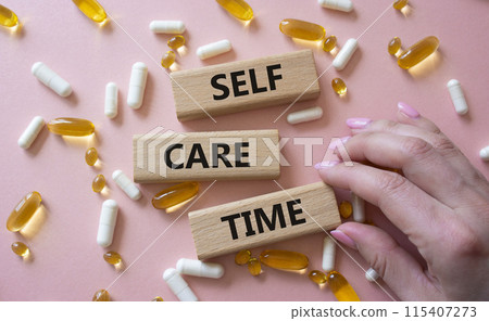 Self-care Time symbol. Concept words Self-care Time on wooden blocks. Beautiful pink background with pills. Doctor hand. Healthcare and Self-care Time concept. Copy space. Self-care Time symbol. Concept words Self-care Time on wooden blocks. Beautiful pink background with pills. Doctor hand. Healthcare and Self-care Time concept. Copy space. 115407273