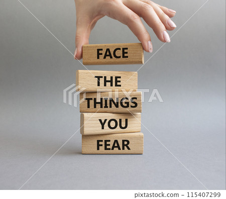 Face the things you fear symbol. Wooden blocks with words Face the things you fear. Beautiful grey background. Businessman hand. Business and Face the things you fear concept. Copy space. 115407299