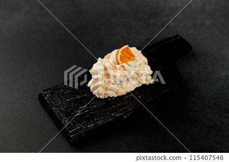 Meringue roll. Whipped proteins and sugar, filling - cream cheese based on soft cheese and cream on a black cutting board Meringue roll. Whipped proteins and sugar, filling - cream cheese based on soft cheese and cream on a black cutting board 115407546