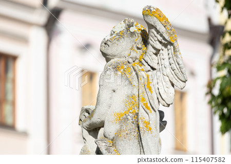 Plague column detail - old statue of angel with blurred historical buildings on background, Telc, Czechia Plague column detail - old statue of angel with blurred historical buildings on background, Telc, Czechia 115407582
