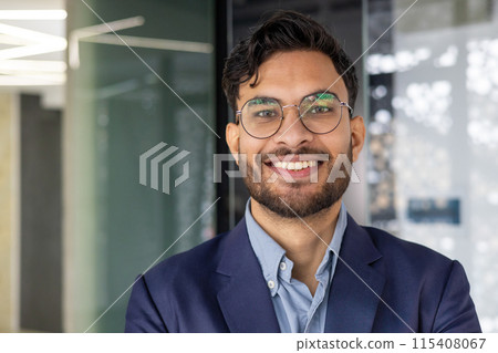 Portrait of a confident young professional smiling indoors in a modern office. Perfect for business, corporate, and workplace concepts. Portrait of a confident young professional smiling indoors in a modern office. Perfect for business, corporate, and workplace concepts. 115408067