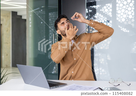 Man using eye drops while working at the office with laptop. Workplace discomfort and eye care. 115408082