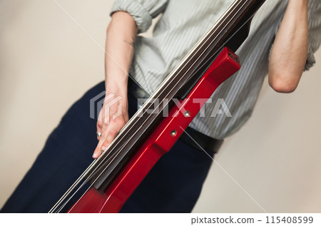 A man playing red electric double bass. Close-up photo 115408599