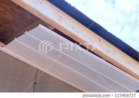 Worker installation of upvc soffit boards on roof corners ceiling rafters house Worker installation of upvc soffit boards on roof corners ceiling rafters house 115408727