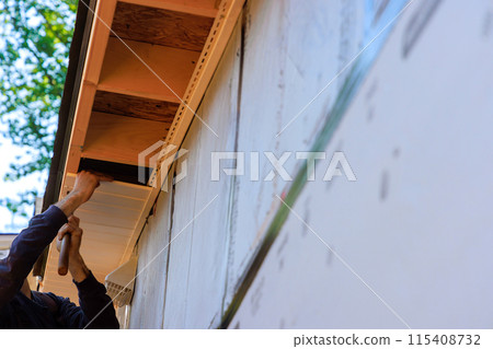 Vinyl white uPVC soffit board below facia roof installed along roofline of house. Vinyl white uPVC soffit board below facia roof installed along roofline of house. 115408732