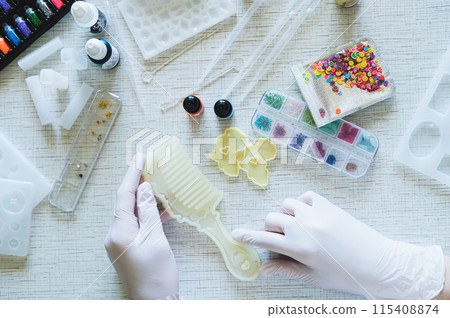 Female hands in gloves hold a mold for making a comb from epoxy resin 115408874