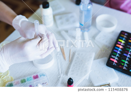 Female hands in gloves pour epoxy resin into a bowl for making jewelry Female hands in gloves pour epoxy resin into a bowl for making jewelry 115408876