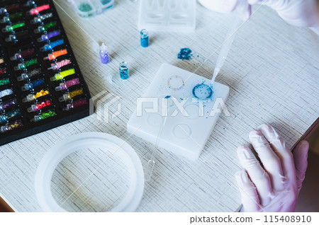 Children's hands in gloves fill a mold for making a ring with epoxy resin 115408910