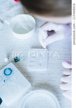 Female hands in gloves decorate earrings made of epoxy resin in the form vertical view Female hands in gloves decorate earrings made of epoxy resin in the form vertical view 115408918